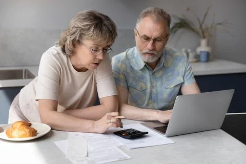 Happy middle aged family managing household expenditures. Stock Photos