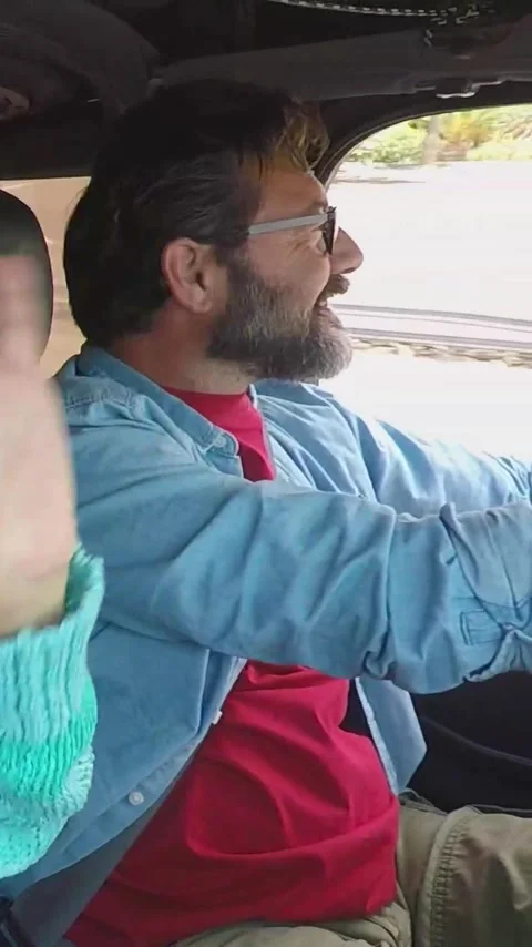 Happy middle-aged man with a beard and glasses driving his convertible car Stock Footage 346605493