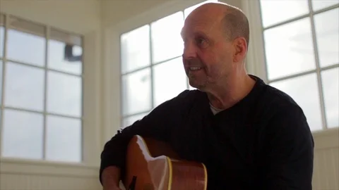 Happy middle aged man playing an acoustic guitar. Видео 88407202