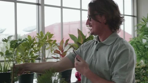 A happy middle-aged man is using a smartphone to take photos with plants. Stock Footage 143470289