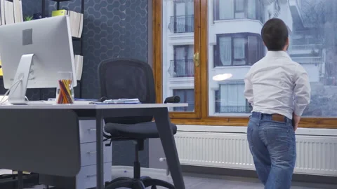 Happy midget man working in his office. He gets up and looks outside. Stock Footage 230977964
