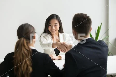 Happy millennial asian applicant getting hired shaking hand of h Stock Photos
