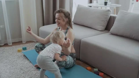 Happy mindful single mother doing morning exercises in yoga pose with kid Video stock 130824218