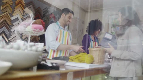 Happy mixed ethnicity store assistants take payment from a customer Stock Footage