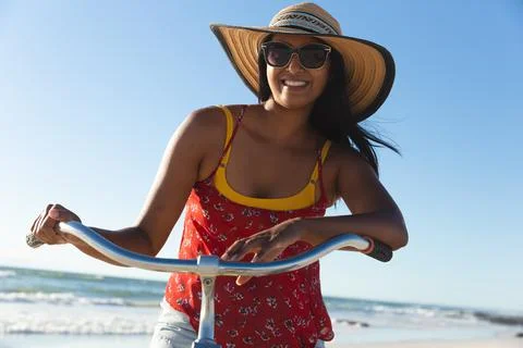 Happy mixed race woman having fun on beach holiday on bicycle Stock Photos