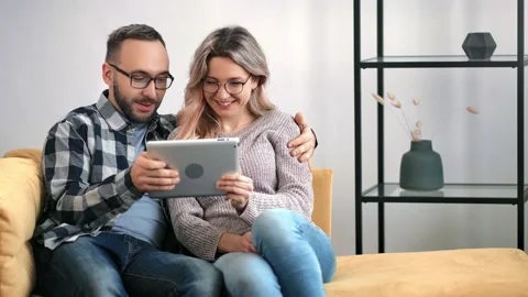 Happy modern couple use tablet pc together smiling looking at screen. Medium Stock-Footage 150586539