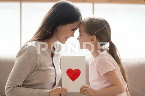 Happy mom and kid daughter holding greeting card with heart Stock Photos