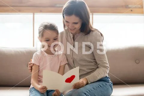 Happy mom and little kid daughter holding reading greeting card Stock Photos