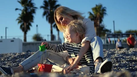 Happy mom and son playing on the pebble beach Video stock 220853440