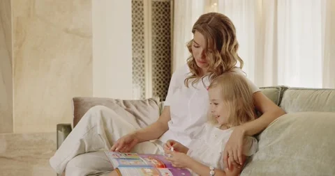 Happy mom relaxing having fun while reading book with small baby girl Stock Footage 217423853
