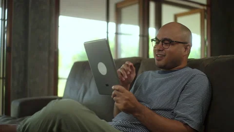 Happy moment man using video call on tablet on sofa in living room in holiday. Stock Footage 269191724