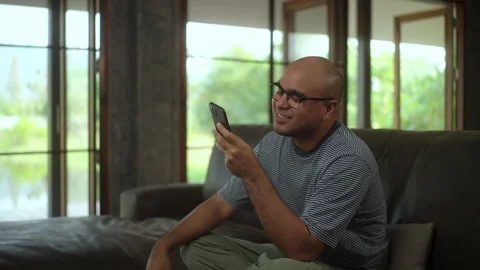 Happy moment Young man using social media on smartphone on sofa in living room. Stock Footage 269193122