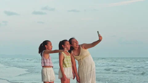 Happy mother and daughters taking video with smartphone on beach during summer Vídeo Stock 340185322