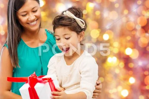 Happy mother and girl with gift box over lights Stock Photos