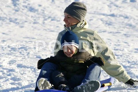 Happy mother and son sledding down the hill Stock Photos