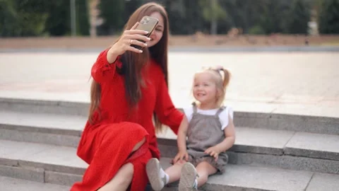 Happy mother holding smartphone while taking selfie with cute daughter in park Stock Footage 244245929