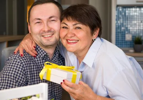 Happy mother hugging son while holding present. Mother's day or 8 march conce Stock Photos