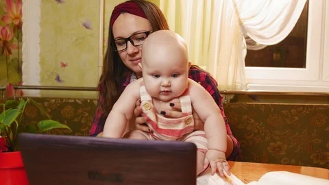 Happy mother keep her chubby baby at kitchen and looking to screen laptop Stock Footage 122246035