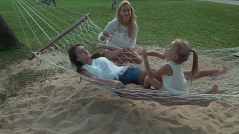 Happy mother shakes her daughters in hammock stock footage video Stock Footage