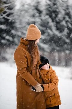 Happy mother standing in embrace with son at snowy park Stock Photos
