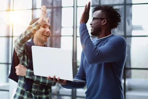 Happy multicultural programmers giving high five while working in office togethe Foto stock