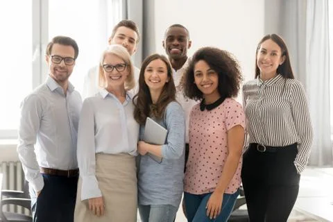 Happy multicultural work team looking at camera posing in office Stock Photos