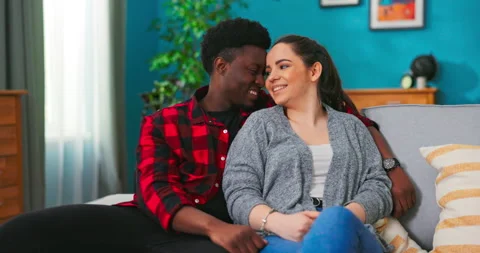 Happy multiethnic couple bonding to each other and smiling while sitting on Stockbeeldmateriaal 152355813