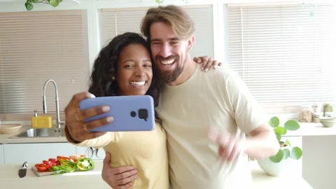 Happy multiethnic couple taking a selfie in the kitchen of their new apartment. Video stock 169105161