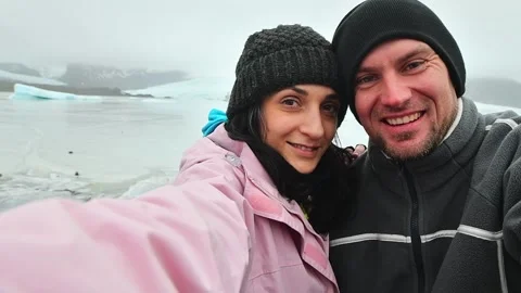 Happy multiethnic couple taking selfie by glacier lagoon in Iceland. Two to.. Stockbeeldmateriaal 249787933