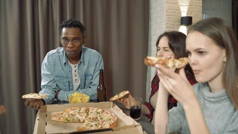 Happy multiethnic friends drinking beer eating pizza in the living room at home Stock Footage 124038245