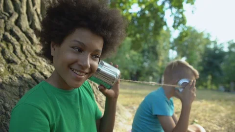 Happy multiethnic friends talking through cans, happy childhood without gadgets 動画素材 117205183