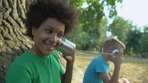 Happy multiethnic friends talking through cans, happy childhood without gadgets 動画素材 117209472