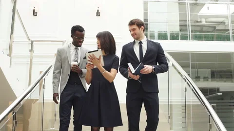 Happy multiracial business people walking down on stairs together with digital Stock Footage