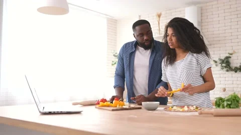 Happy multiracial couple preparing meal together in front of a laptop Stock Footage 151435879