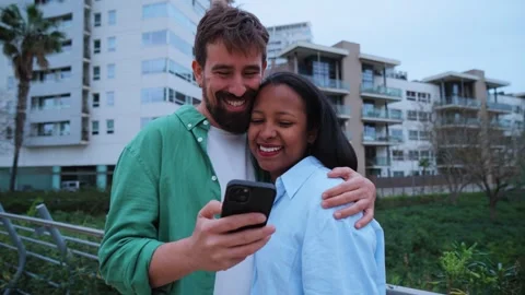 Happy multiracial couple using smartphone outdoors in the city Stock Footage 315874724