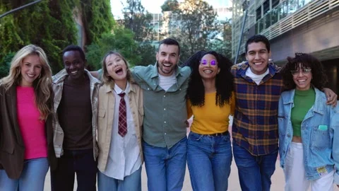 Happy multiracial group hugging each other walking towards de camera outdoors Stock Footage 285221403