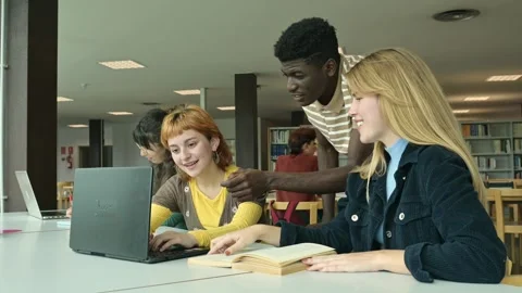 Happy multiracial students smiling and discussing task at laptop in library Stock Footage 269347376