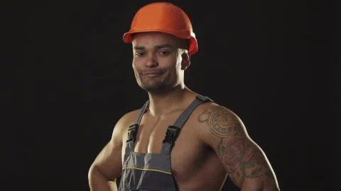 Happy muscular African male builder in hardhat smiling showing thumbs up Stock Photos