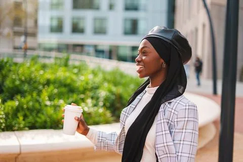 Happy Muslim black woman drinking coffee and laughing Stock Photos