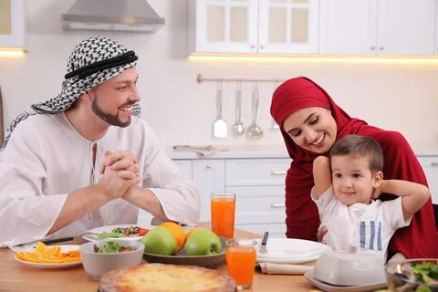 Happy Muslim family eating together at table in kitchen Stock Photos