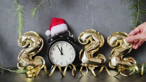 Happy new year 2022 background. Hand puts Metallic balloons golden color on gray Stock Footage 164315199
