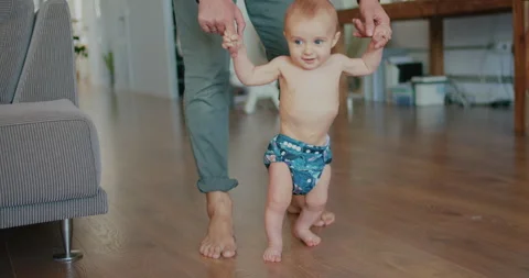 Happy Newborn baby boy doing his first steps with daddy help at home. Lovely 動画素材 132107553