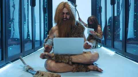 Happy nomadic caveman sitting on floor with laptop, dancing a victory dance Stock Footage 121123096