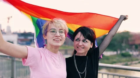 Happy non-binary couple waving rainbow flag Stock Footage 161019197