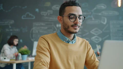 Happy office worker Arab man using laptop computer in workplace smiling Stock Footage 133027280