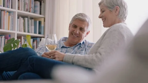 Happy old couple drinking wine relaxing on sofa at home making toast celebrating Video stock 111715046