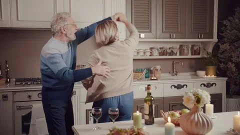 Happy old couple having fun drinking wine talking, preparing meal in kitchen Stock Footage 234989839