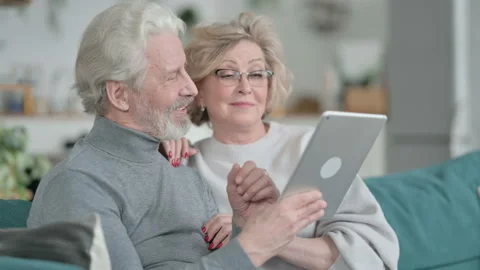 Happy Old Couple Sitting on Sofa and using Tablet Stock Footage 148202546