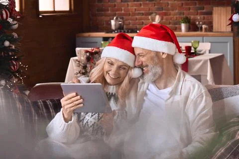 Happy old couple using digital tablet feeling joy have virtual Christmas party. Stock Photos