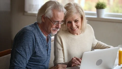 Happy old couple using laptop talking together doing online shopping Stock Footage 107065151